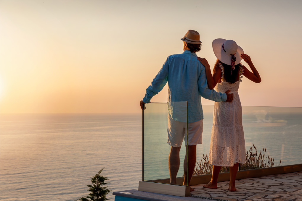 Un couple se tient sur un balcon donnant sur l'océan.
