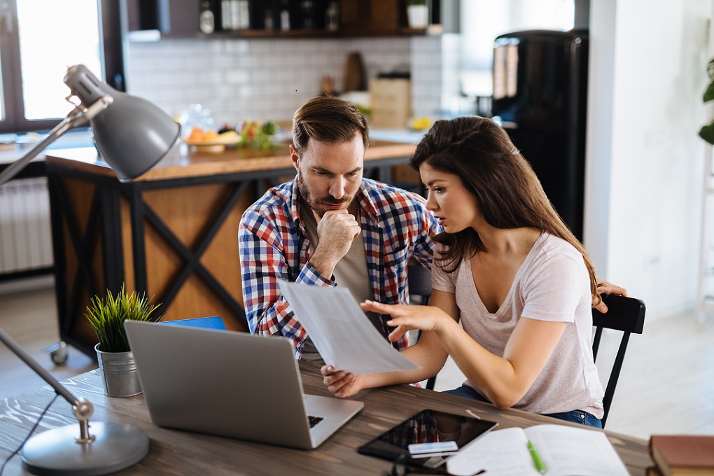 Un couple analyse l'état de leurs finances, assis à la table de la cuisine Un couple analyse l'état de leurs finances, assis à la table de la cuisine