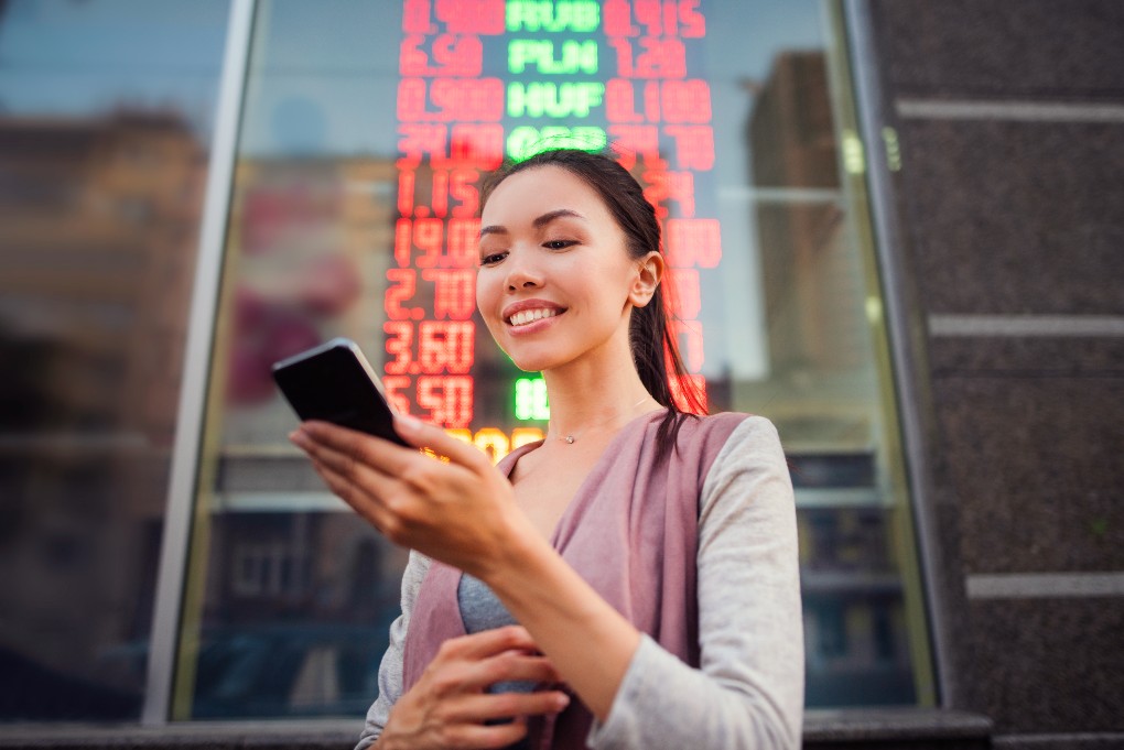Marché boursier femme investissement négociation Une jeune femme qui utilise son téléphone pour consulter ses investissements dans le marché boursier.